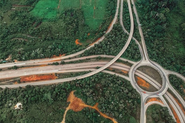 Aerial view of a complex highway interchange with overlapping ramps in a forested area.