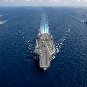 Aircraft carrier underway on open ocean with escort vessels